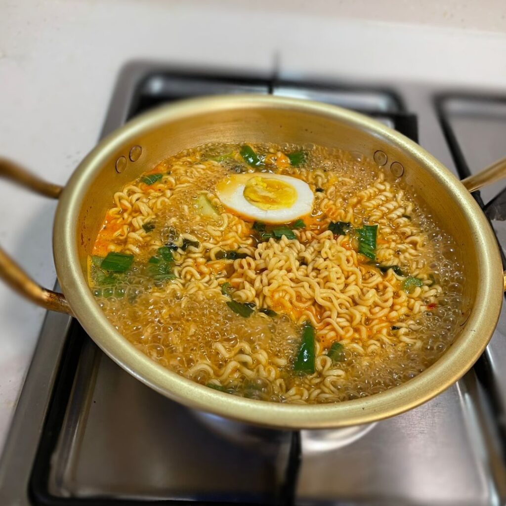 A steaming bowl of Korean Ramen served with eggs and vegetables, symbolizing warmth and connection.